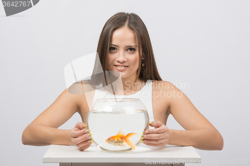 Image of Beautiful girl hugged an aquarium with goldfish
