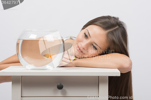 Image of Beautiful girl dreams and sees a goldfish in an aquarium