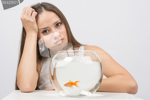 Image of Upset young girl sitting next to the fishbowl