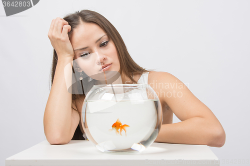 Image of Upset young girl looking at goldfish in a fishbowl