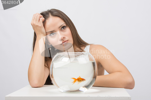 Image of Thoughtful young girl looking at goldfish in a fishbowl