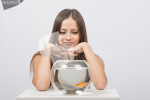 Image of Beautiful girl looks at the aquarium presented with goldfish