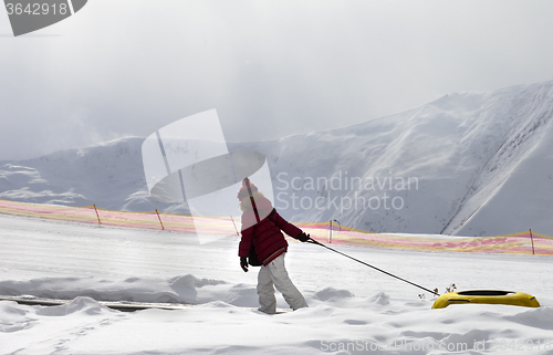 Image of Girl with snow tube at sun day