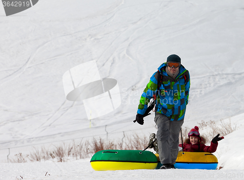 Image of Father and daughter with snow tube at sun day