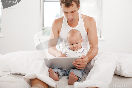 Image of Young father and his nine months old son with digital tablet