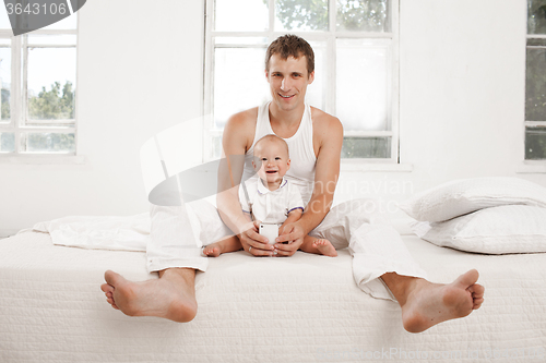 Image of young father with his nine months old son on the bed at home