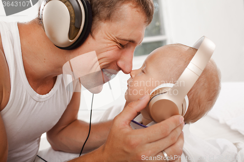 Image of young father with his nine months old som on the bed at home