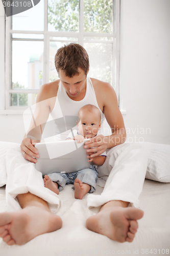 Image of Young father and his nine months old son with digital tablet