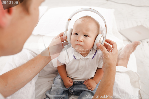 Image of young father with his nine months old som on the bed at home