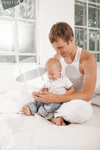 Image of young father with his nine months old son on the bed at home