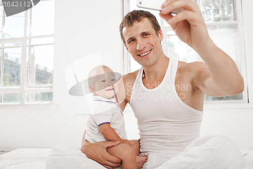 Image of young father with his nine months old son on the bed at home