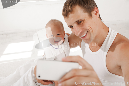 Image of young father with his nine months old son on the bed at home