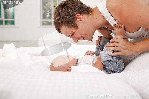 Image of young father with his nine months old son on the bed at home