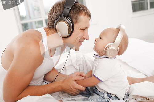 Image of young father with his nine months old som on the bed at home