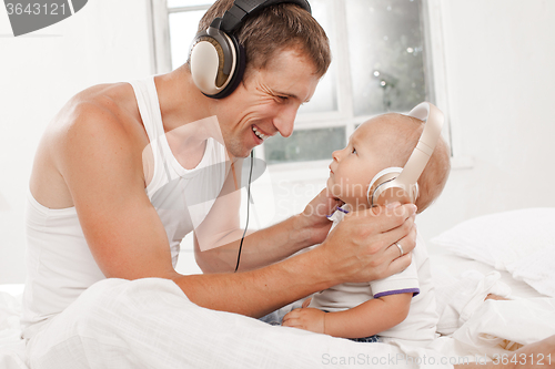 Image of young father with his nine months old som on the bed at home