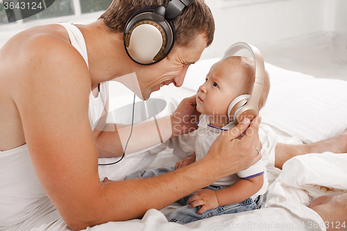 Image of young father with his nine months old som on the bed at home