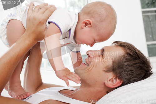 Image of young father with his nine months old son on the bed at home