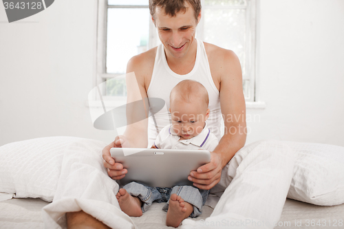 Image of Young father and his nine months old son with digital tablet