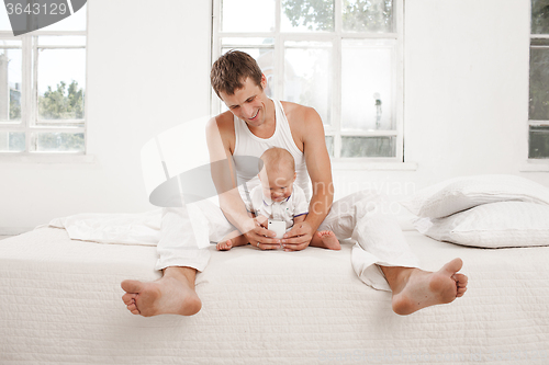 Image of young father with his nine months old son on the bed at home