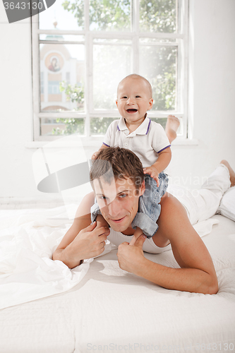 Image of young father with his nine months old son on the bed at home