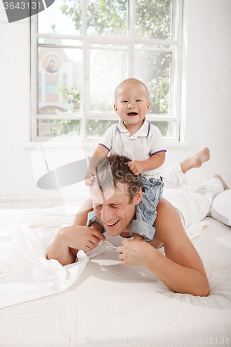 Image of young father with his nine months old son on the bed at home