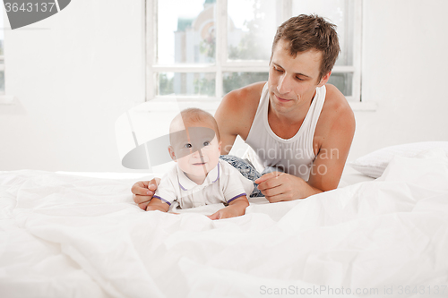 Image of young father with his nine months old son on the bed at home