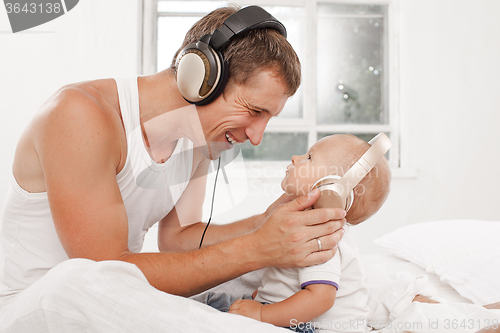 Image of young father with his nine months old som on the bed at home