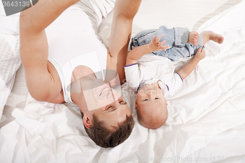 Image of young father with his nine months old son on the bed at home