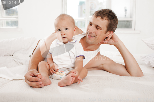 Image of young father with his nine months old son on the bed at home