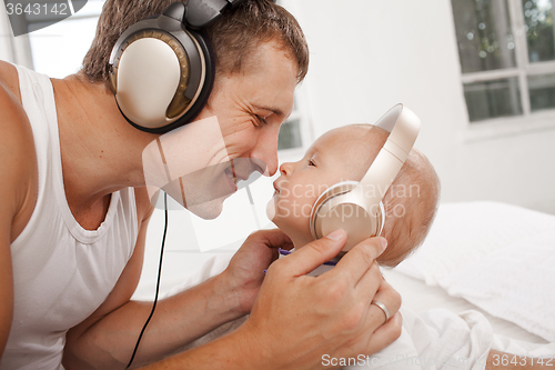 Image of young father with his nine months old som on the bed at home