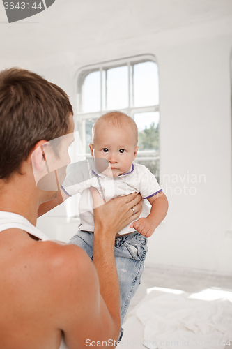 Image of young father with his nine months old son on the bed at home