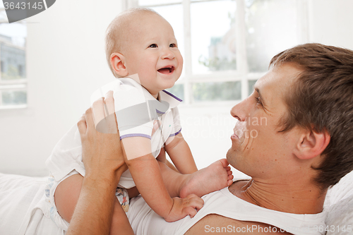 Image of young father with his nine months old son on the bed at home