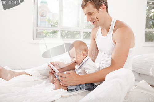 Image of Young father and his nine months old son with digital tablet