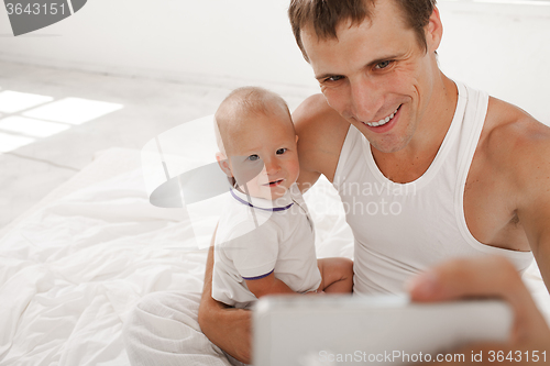 Image of young father with his nine months old son on the bed at home
