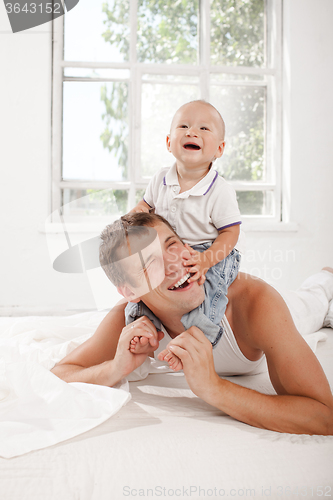 Image of young father with his nine months old son on the bed at home