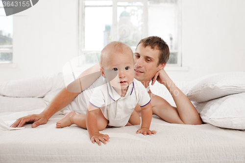 Image of young father with his nine months old son on the bed at home