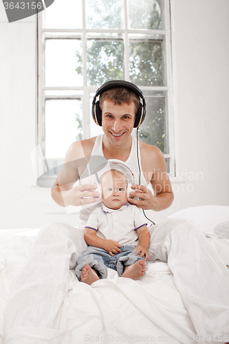 Image of young father with his nine months old som on the bed at home