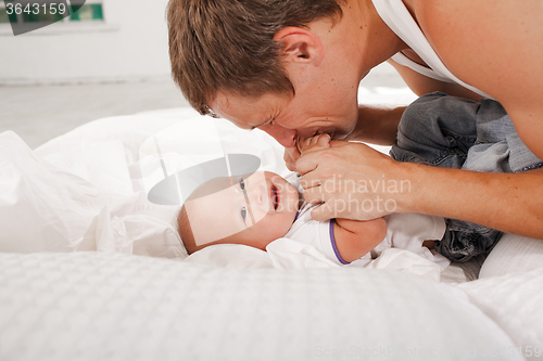 Image of young father with his nine months old son on the bed at home