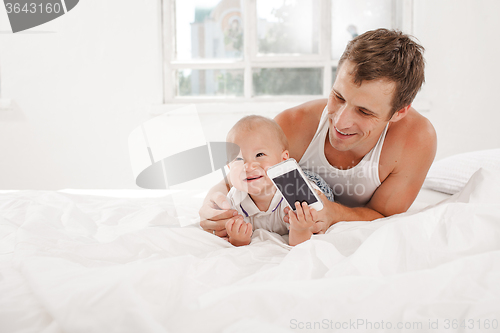 Image of young father with his nine months old son on the bed at home