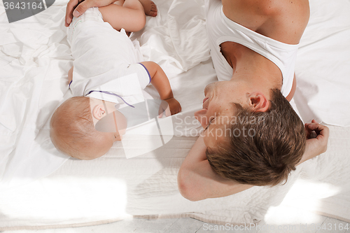 Image of young father with his nine months old son on the bed at home