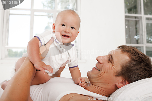 Image of young father with his nine months old son on the bed at home