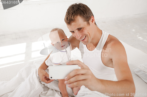 Image of young father with his nine months old son on the bed at home