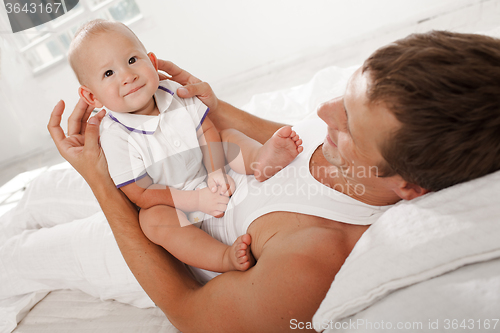 Image of young father with his nine months old son on the bed at home