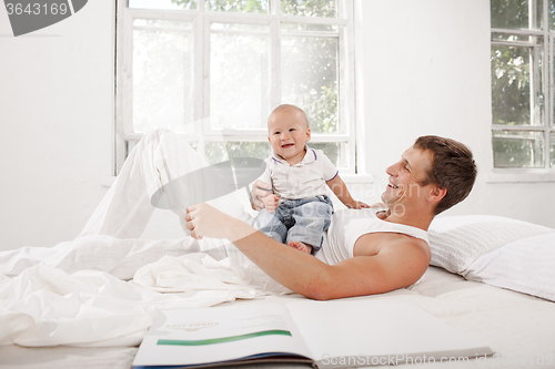 Image of young father with his nine months old son on the bed at home