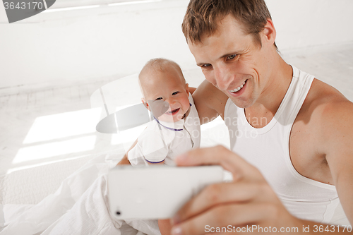 Image of young father with his nine months old son on the bed at home