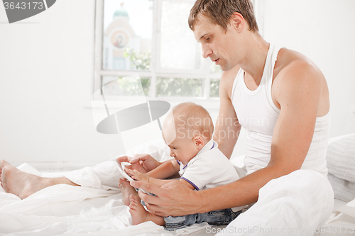 Image of Young father and his nine months old son with digital tablet