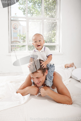 Image of young father with his nine months old son on the bed at home