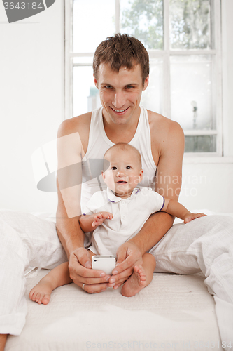 Image of young father with his nine months old son on the bed at home