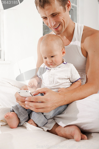 Image of young father with his nine months old son on the bed at home