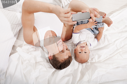 Image of young father with his nine months old son on the bed at home